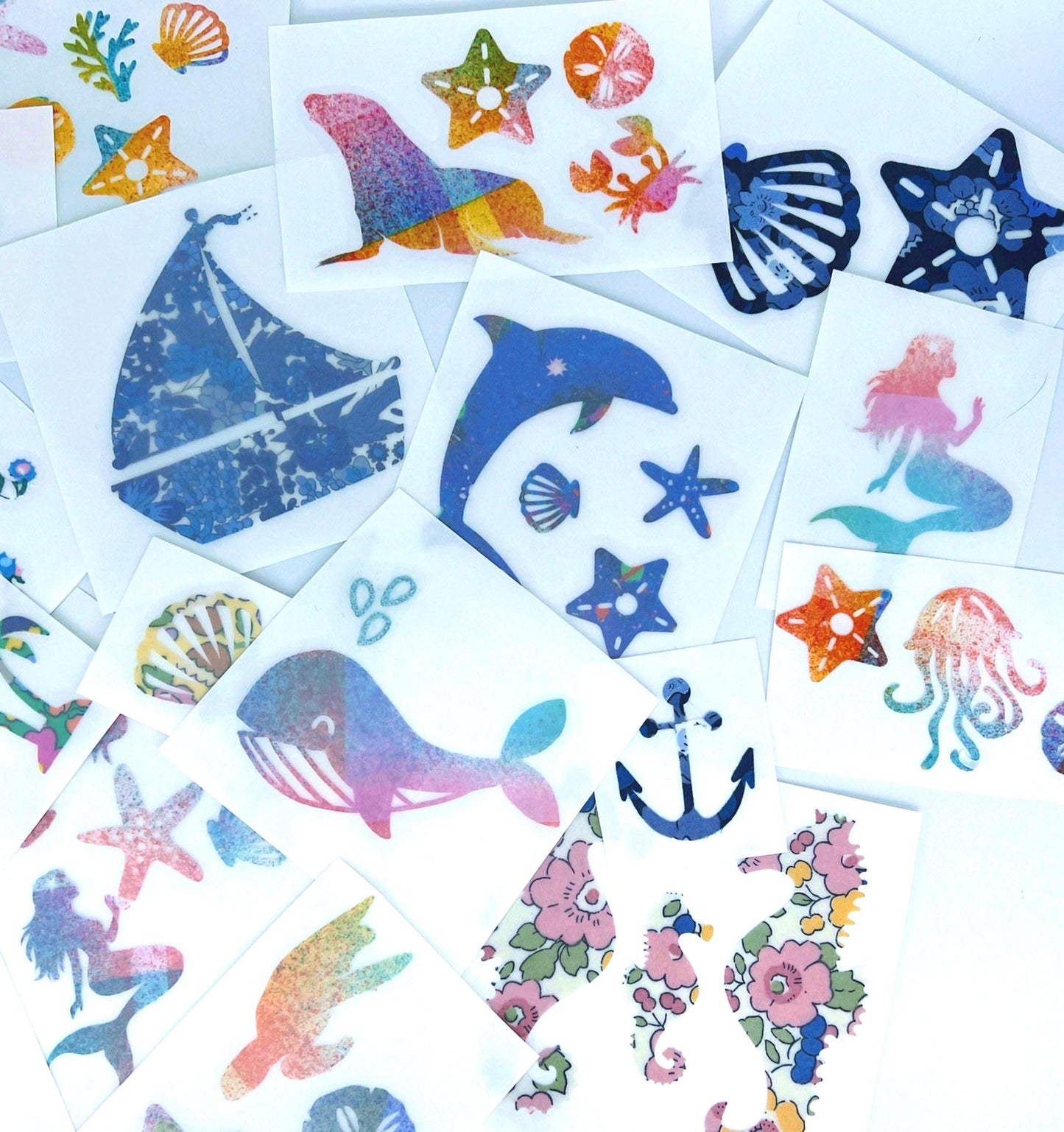 May include: A collection of colorful nautical-themed stickers featuring various sea creatures and elements. Designs include a sailboat, dolphin, starfish, mermaid, whale, seahorse, crab, and seashells. The stickers are on white paper.